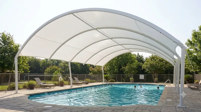 Arched tensile membrane canopy shading a swimming pool and deck
