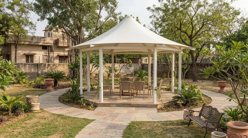 Conical tensile gazebo on a stone plinth in a landscaped garden