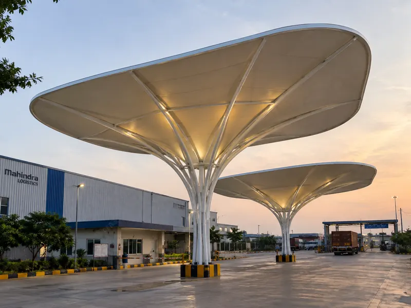 Inverted umbrella tensile canopies lit from beneath at a logistics gate