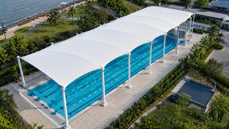 Wave-form tensile membrane roof covering a five-lane outdoor swimming pool